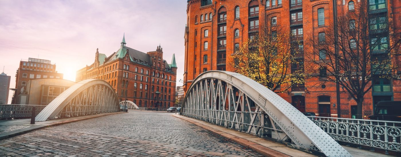 Arch bridge over alster canals with cobbled road in historical Speicherstadt of Hamburg, Germany